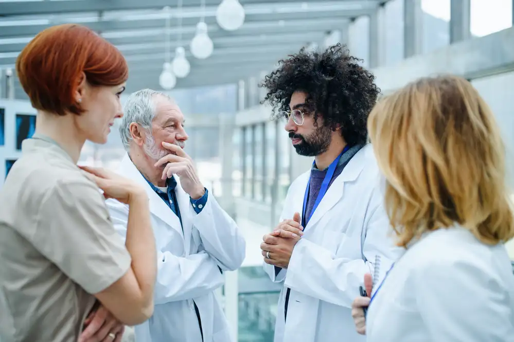 Two healthcare providers in white coats discussing treatment with a middle-aged couple in a modern clinic setting