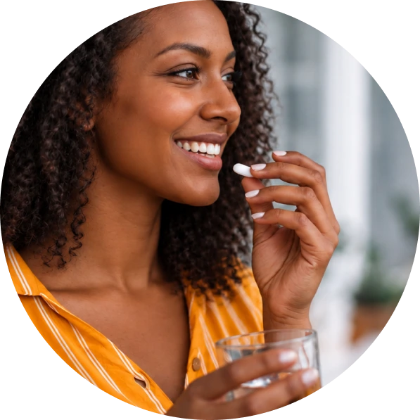 Woman smiling while holding a medication pill and glass of water