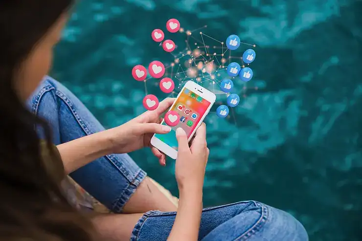 Person holding smartphone with social media icons floating above the screen