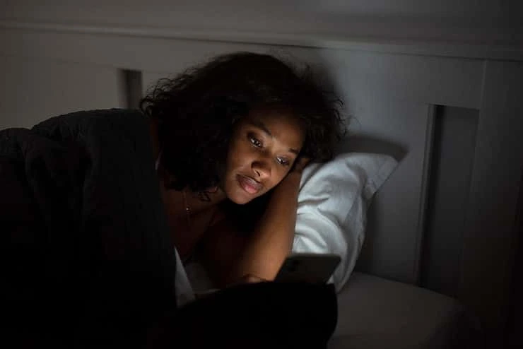 Woman lying awake in bed at night, looking toward camera with concern