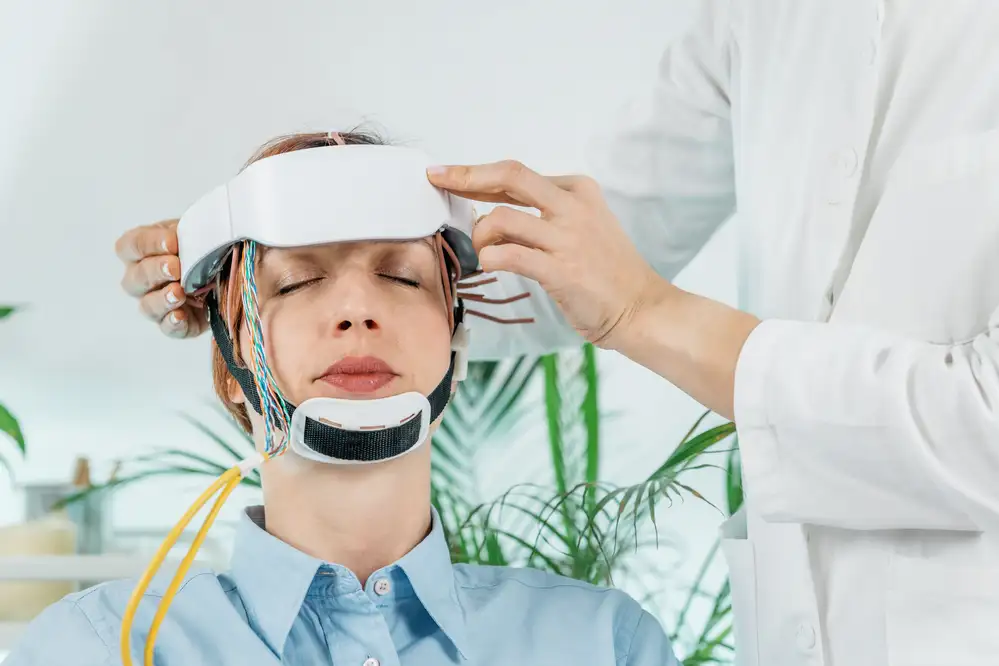 Clinician placing a transcranial magnetic stimulation headset on a patient's head during TMS treatment