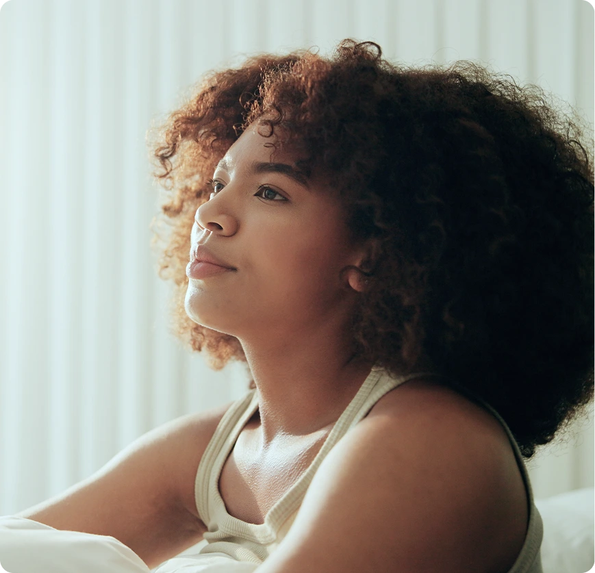 Person in profile looking thoughtfully toward a window with natural light