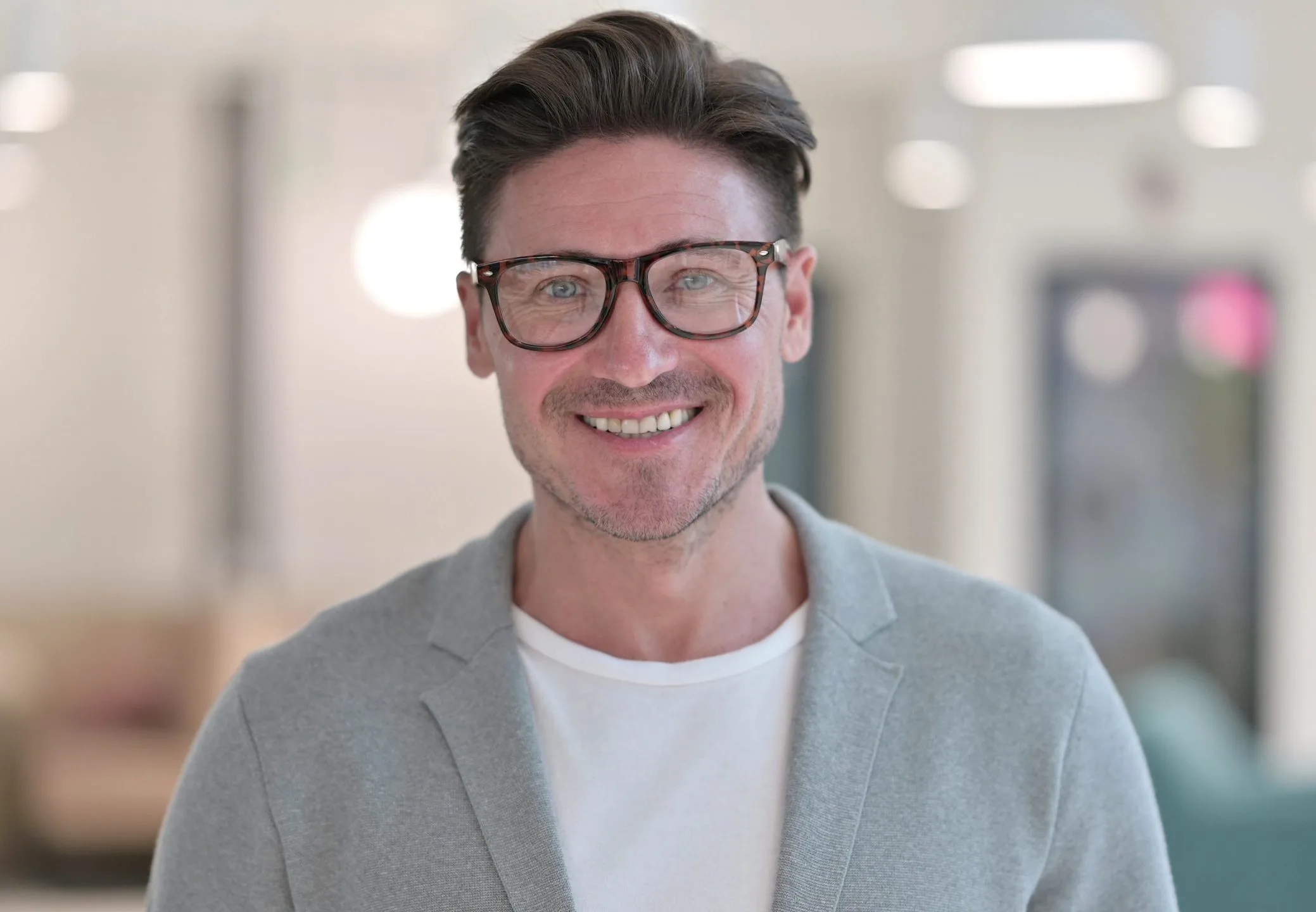 Smiling man wearing glasses in a bright office setting
