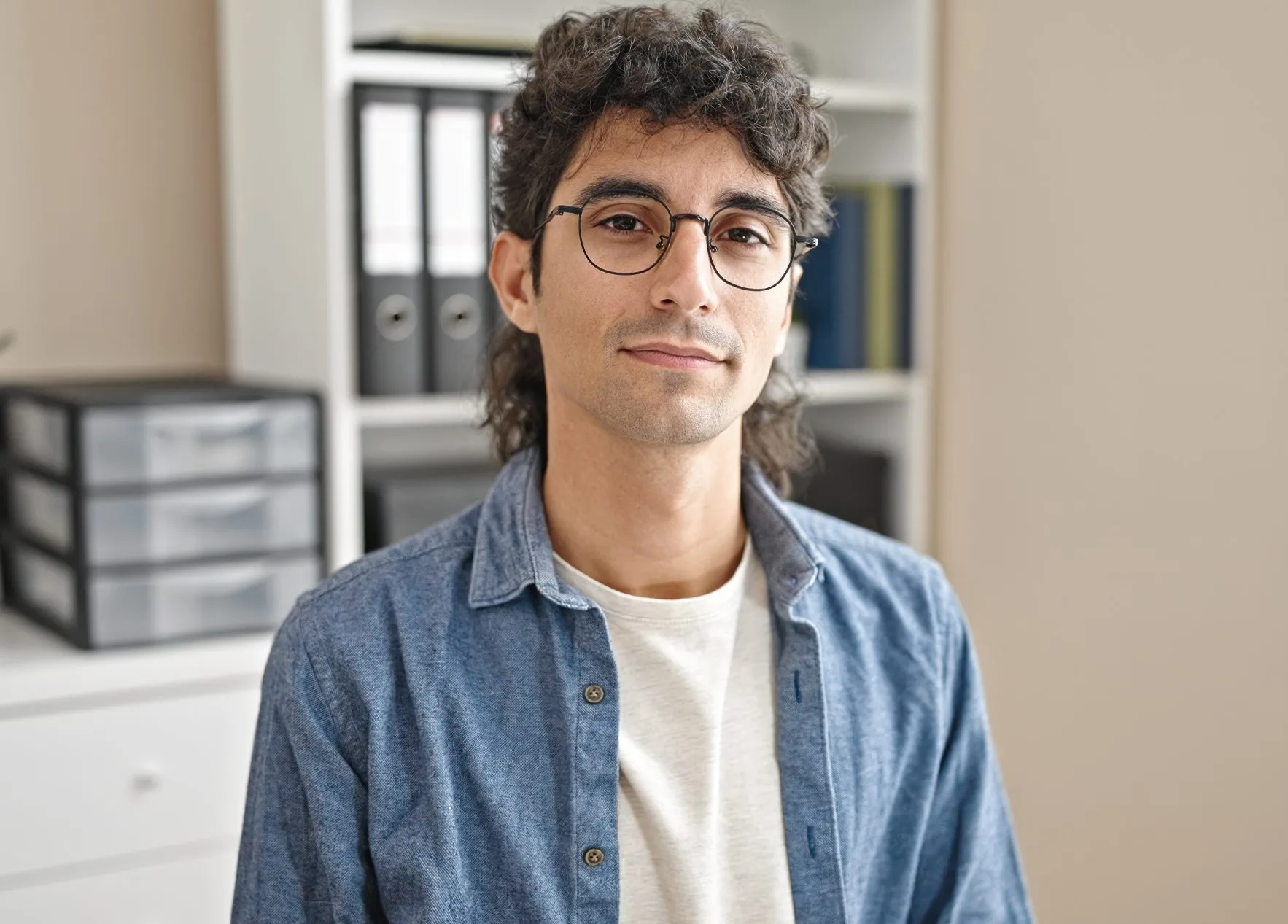 Man in glasses and denim shirt standing in a modern office environment