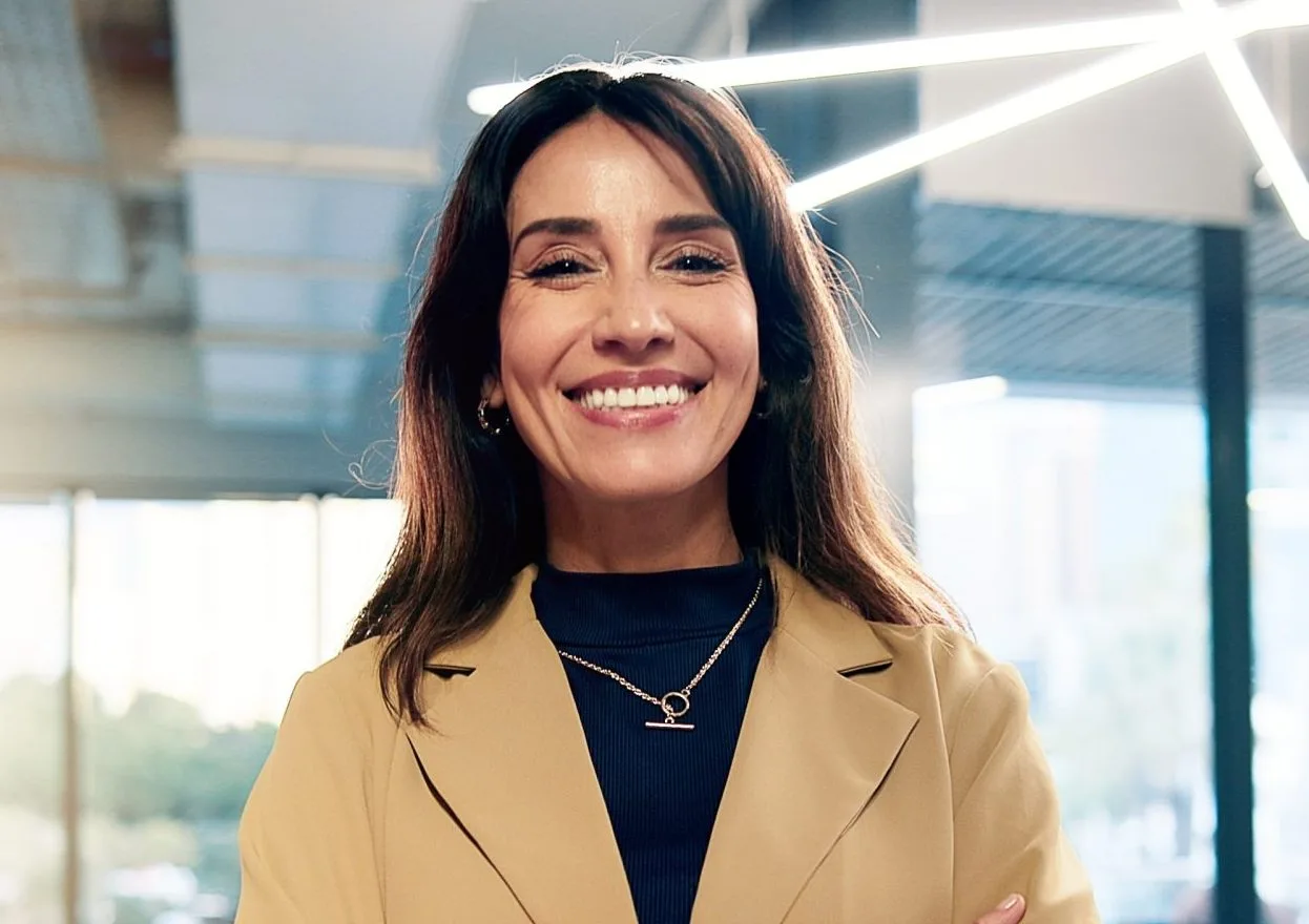 Professional woman smiling with arms crossed in a modern office setting