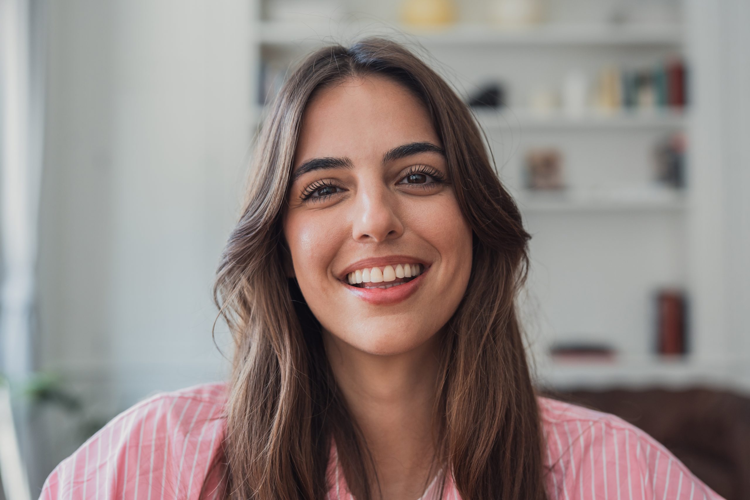 Smiling young woman in a pink shirt against a blurred office background