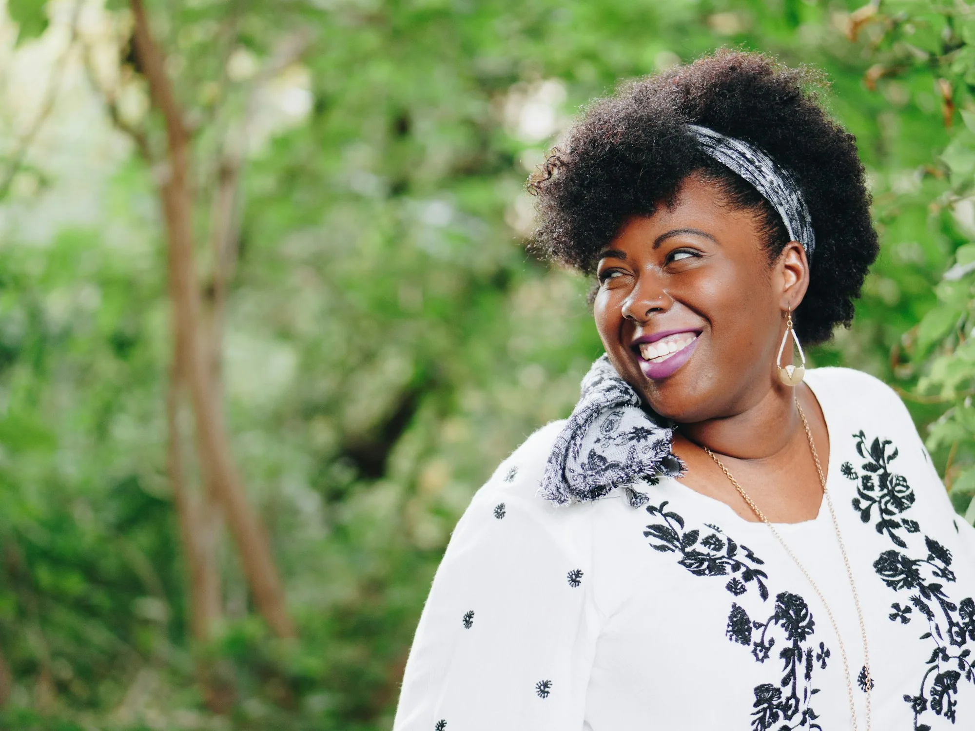 Smiling woman outdoors among green trees