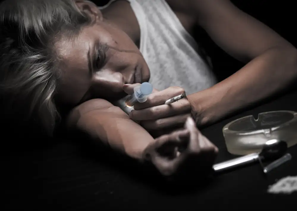Person using intravenous drugs with a spoon and lighter visible, illustrating substance abuse