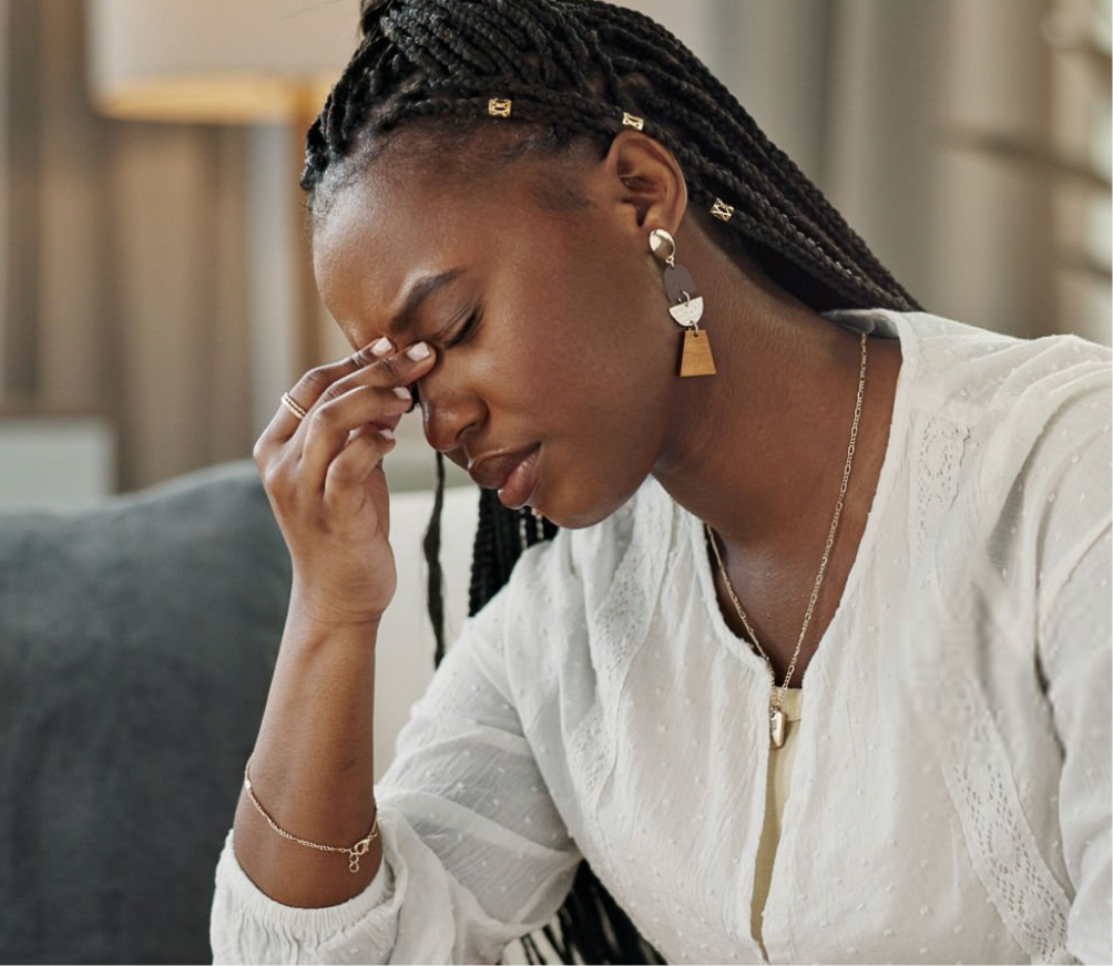 Woman with eyes closed, touching bridge of nose with hand showing fatigue or stress
