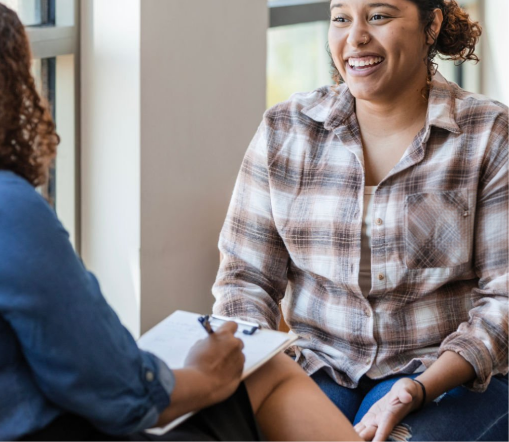 Healthcare provider in plaid shirt smiling while speaking with patient during consultation
