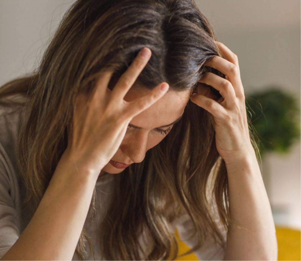Woman with hands on head looking down, appearing overwhelmed or distressed