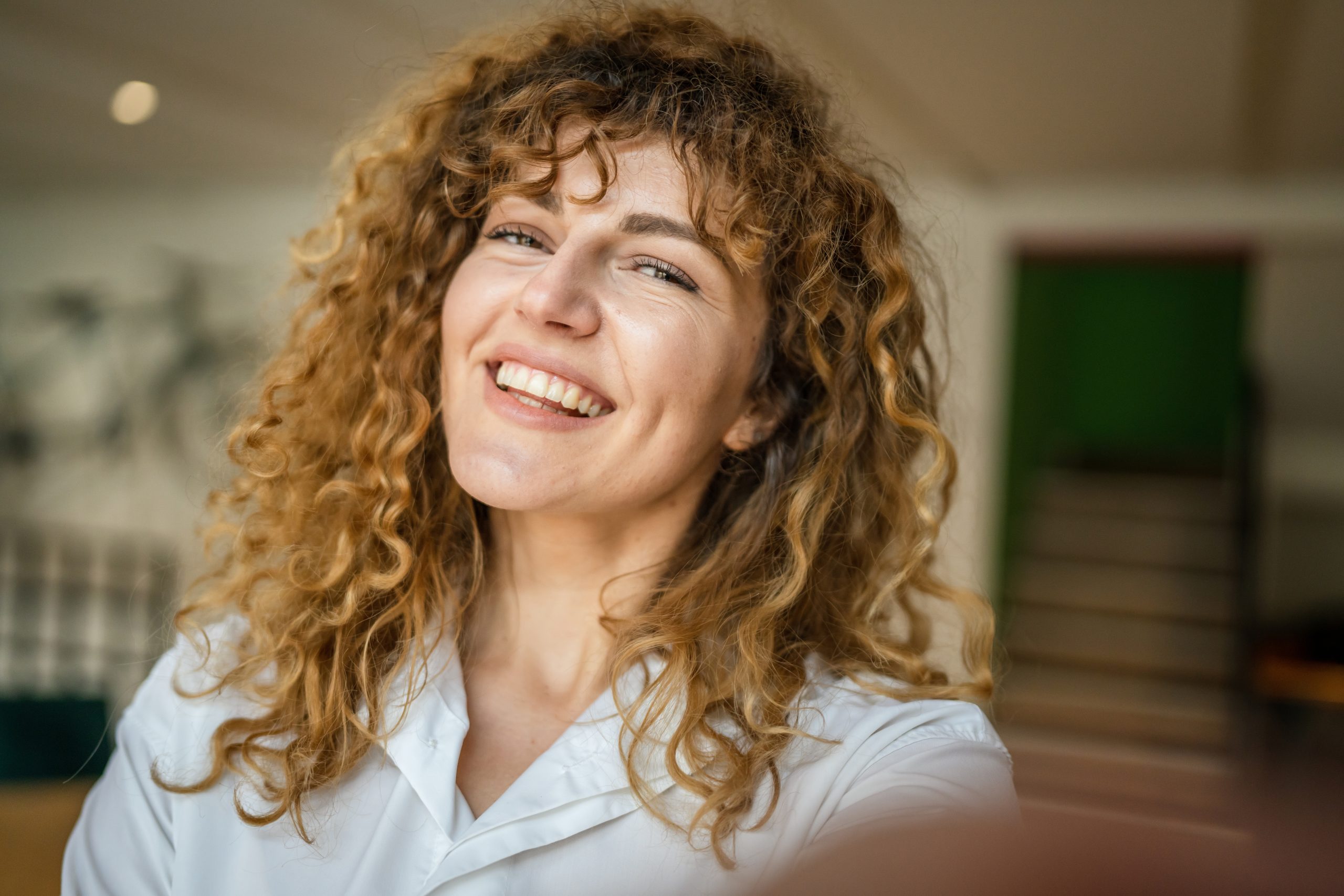 Healthcare professional with curly hair smiling in a clinical setting