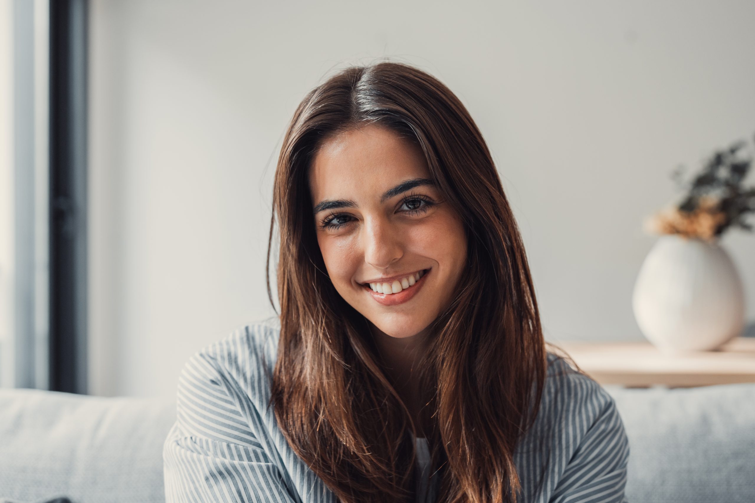 Smiling woman with long brown hair sitting on couch