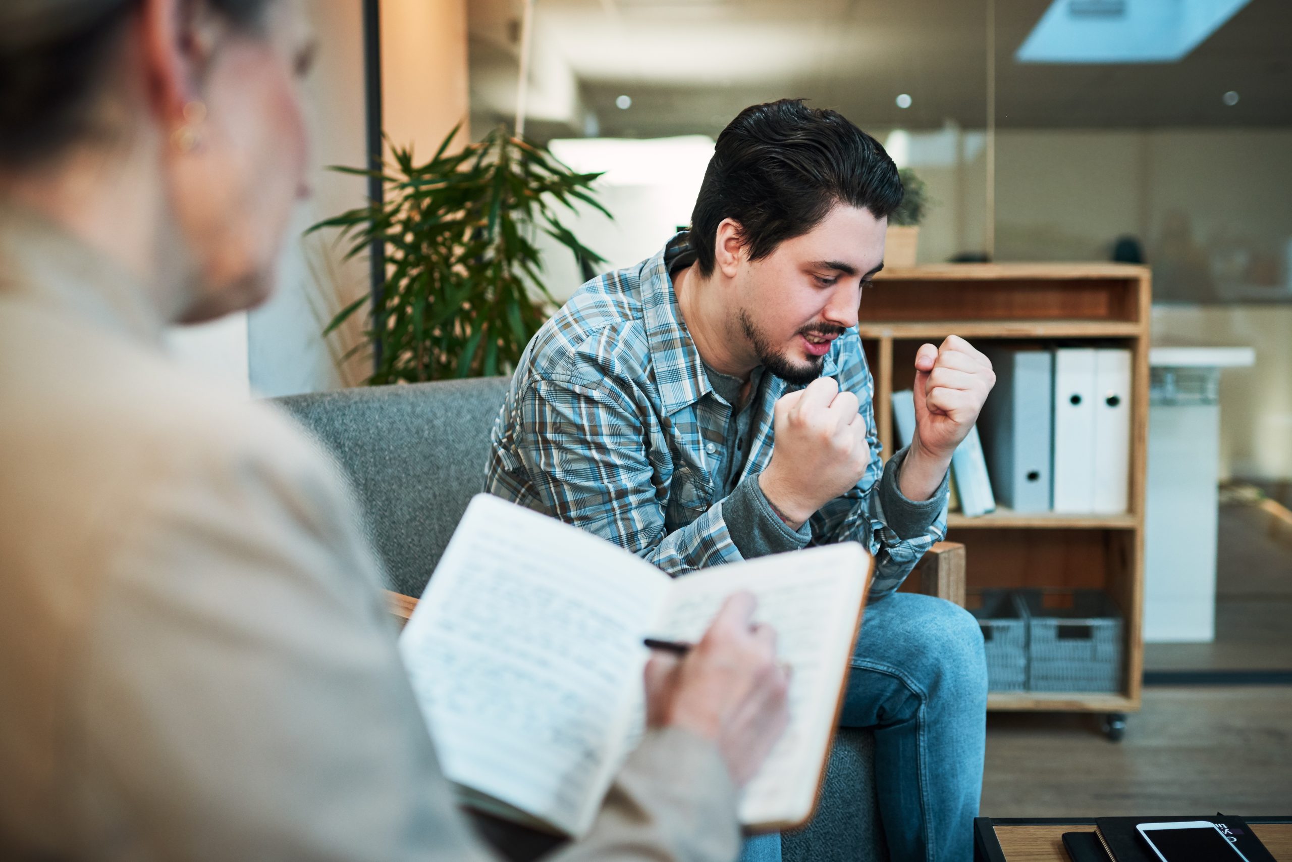 Counselor reviewing notes with man during therapy session in modern office setting