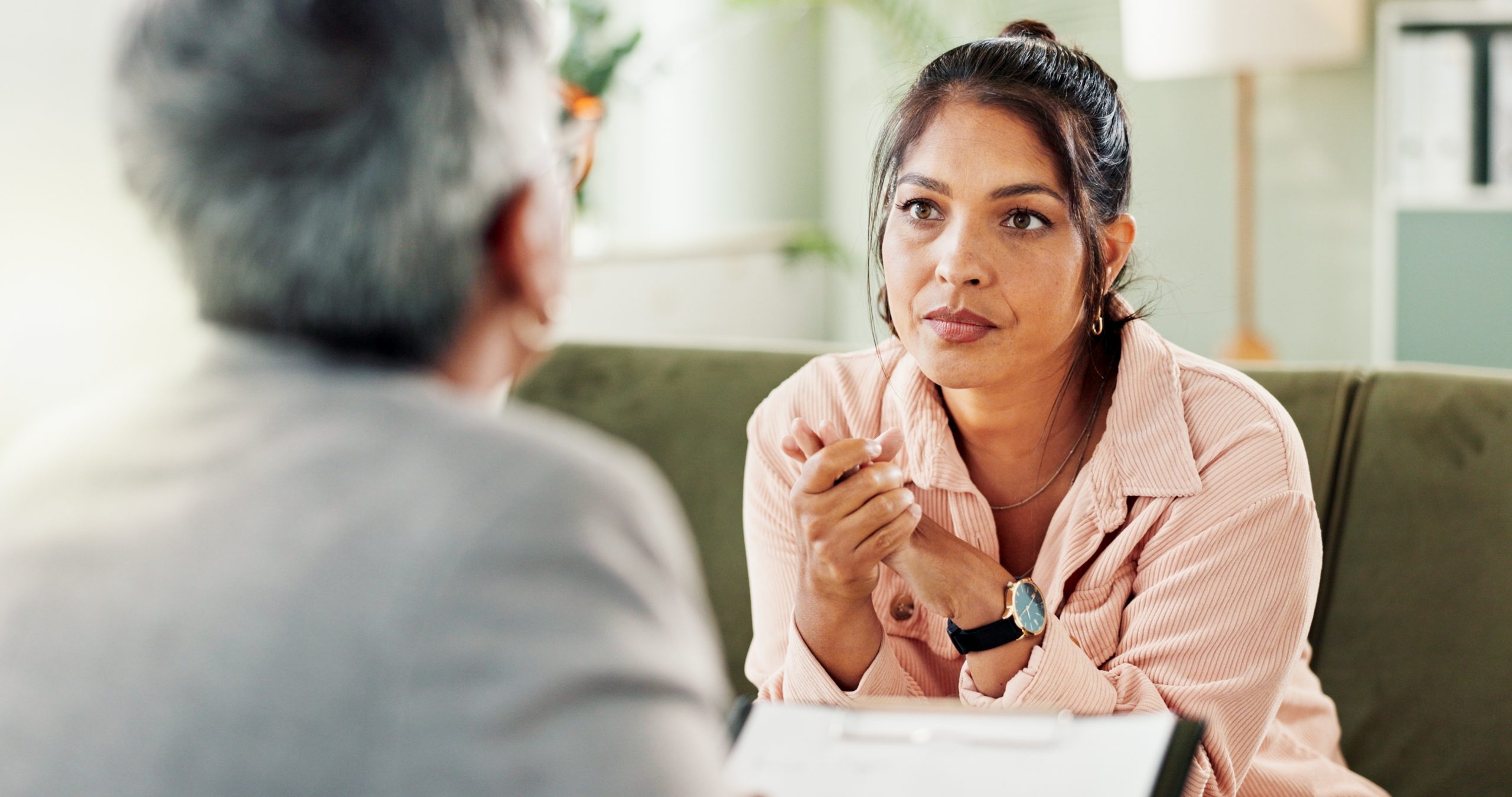 Female therapist in pink shirt speaking with older male patient in therapy session