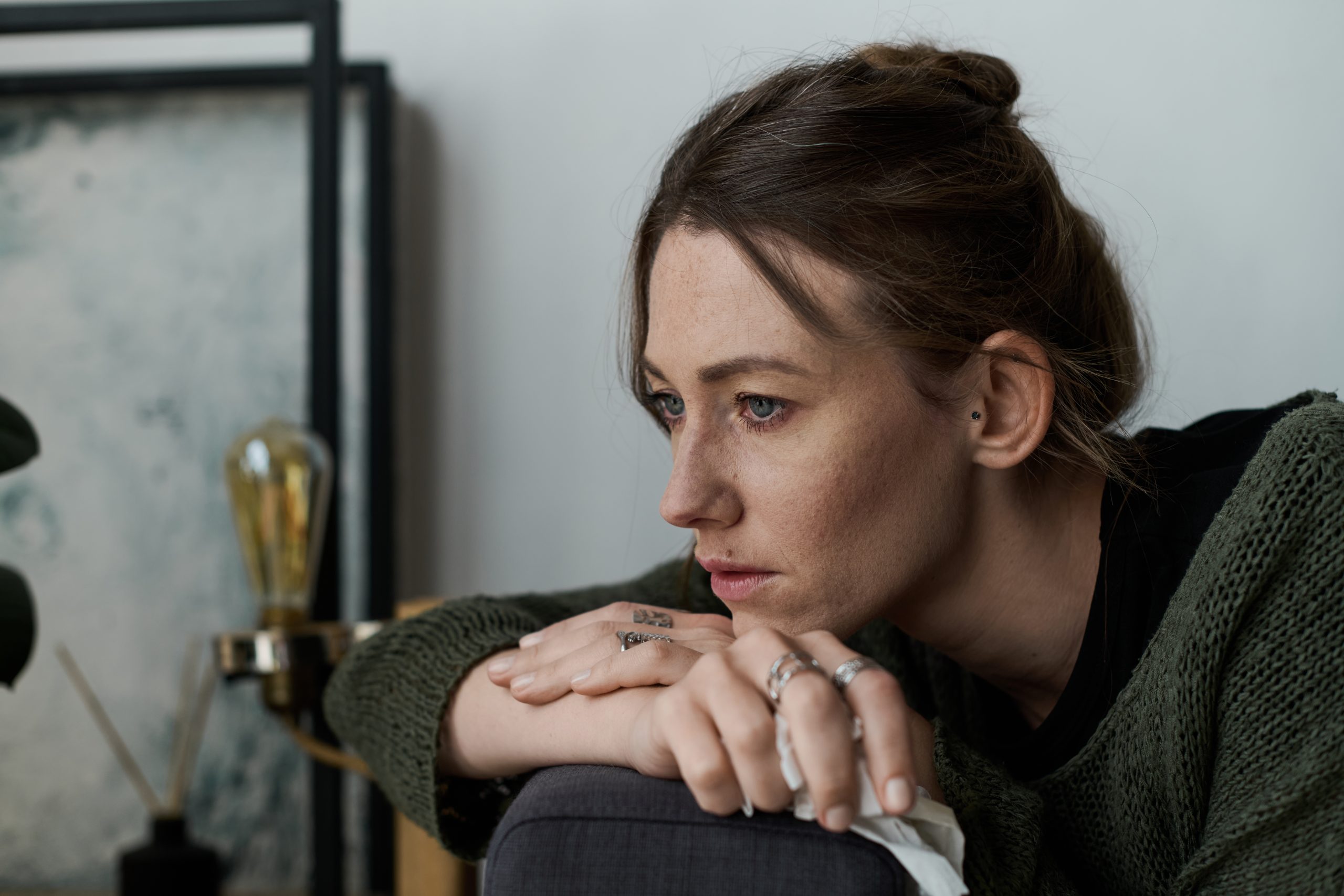 Woman in distress resting head on hand while sitting indoors