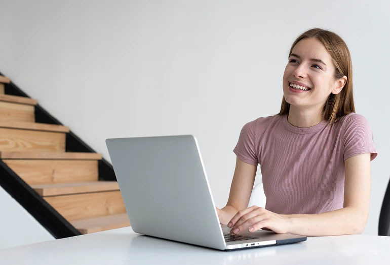 Woman smiling while using a laptop, representing toenail fungus laser treatment insurance information