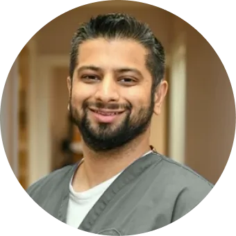 Male podiatrist in gray shirt smiling at camera indoors