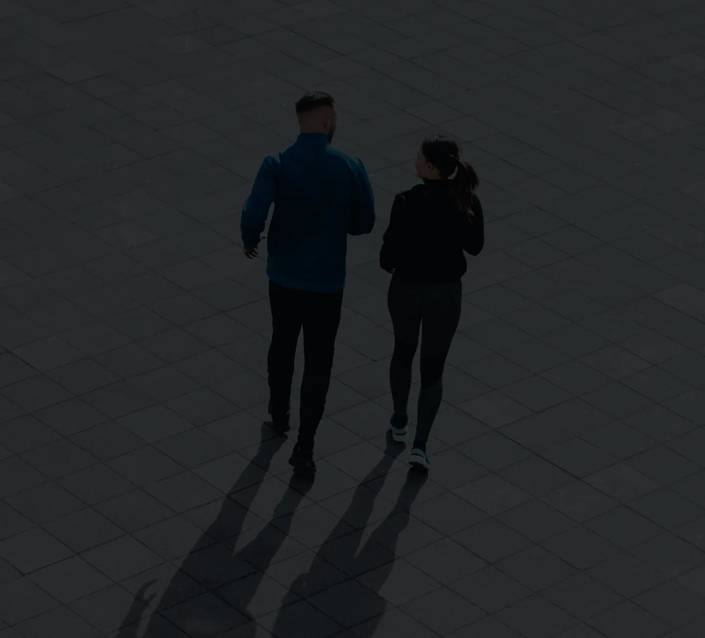 Two people running together on a dark textured ground