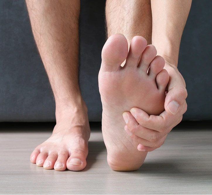 Person holding foot while experiencing pain in sole and toes