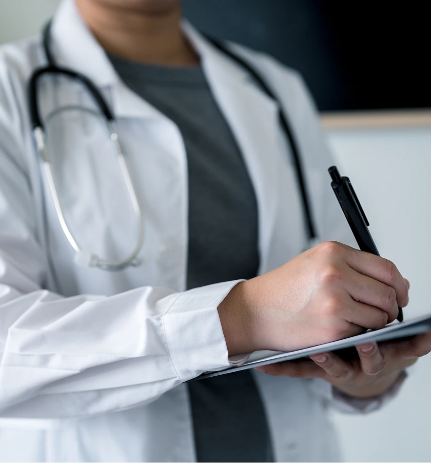 Podiatrist in white coat with stethoscope writing notes on clipboard