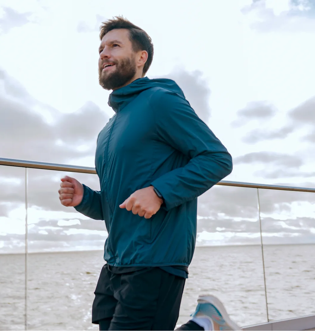 Man jogging on a beach boardwalk against a cloudy sky