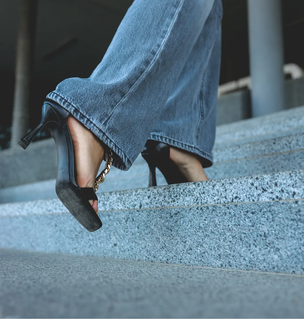 Woman descending concrete stairs wearing black heels and jeans