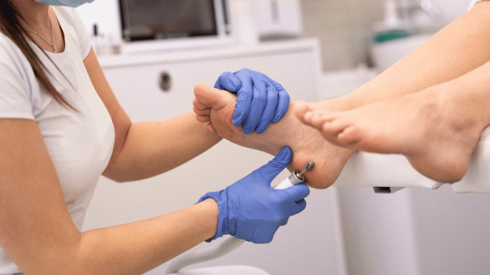 Clinician in blue gloves performing foot examination on patient in clinical setting