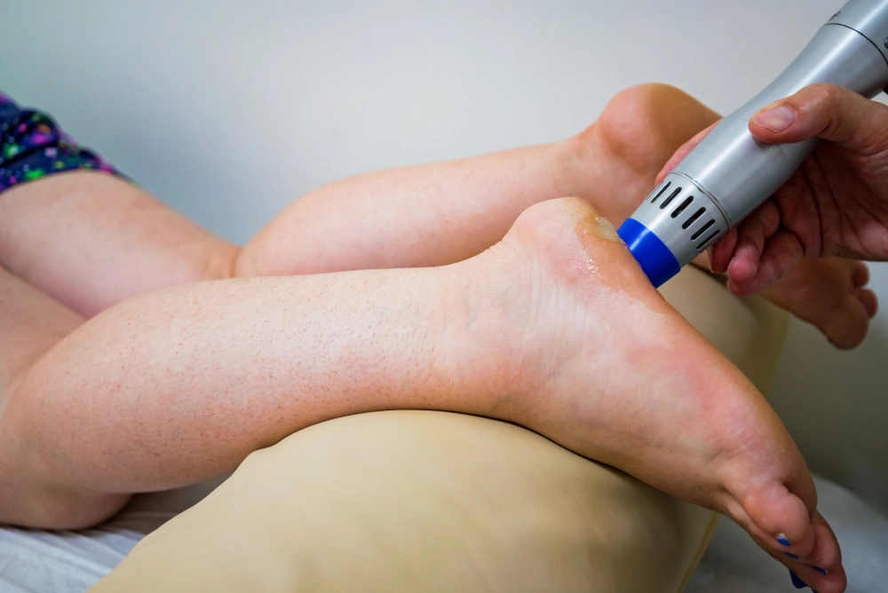 Podiatrist using laser device on patient's foot during treatment