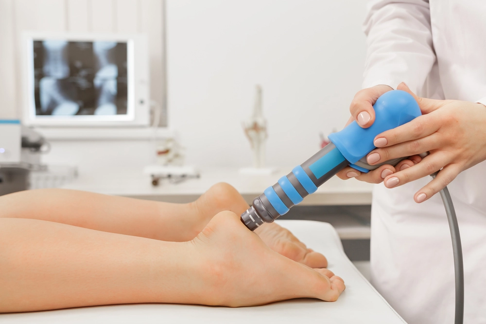 Podiatrist using handheld ultrasound device on patient's foot during treatment