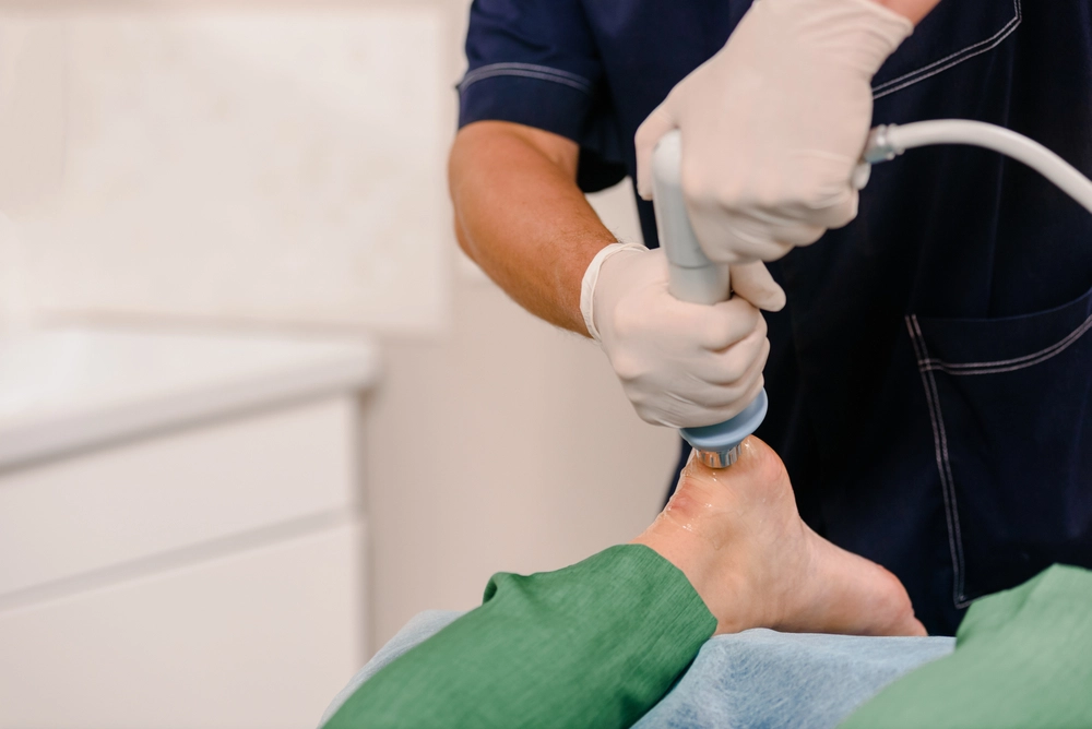 Podiatrist using ultrasound device to examine patient's foot and ankle