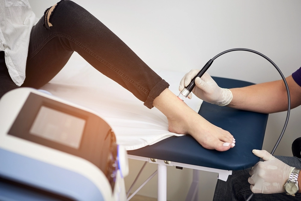 Podiatrist using ultrasound probe on patient's ankle during examination