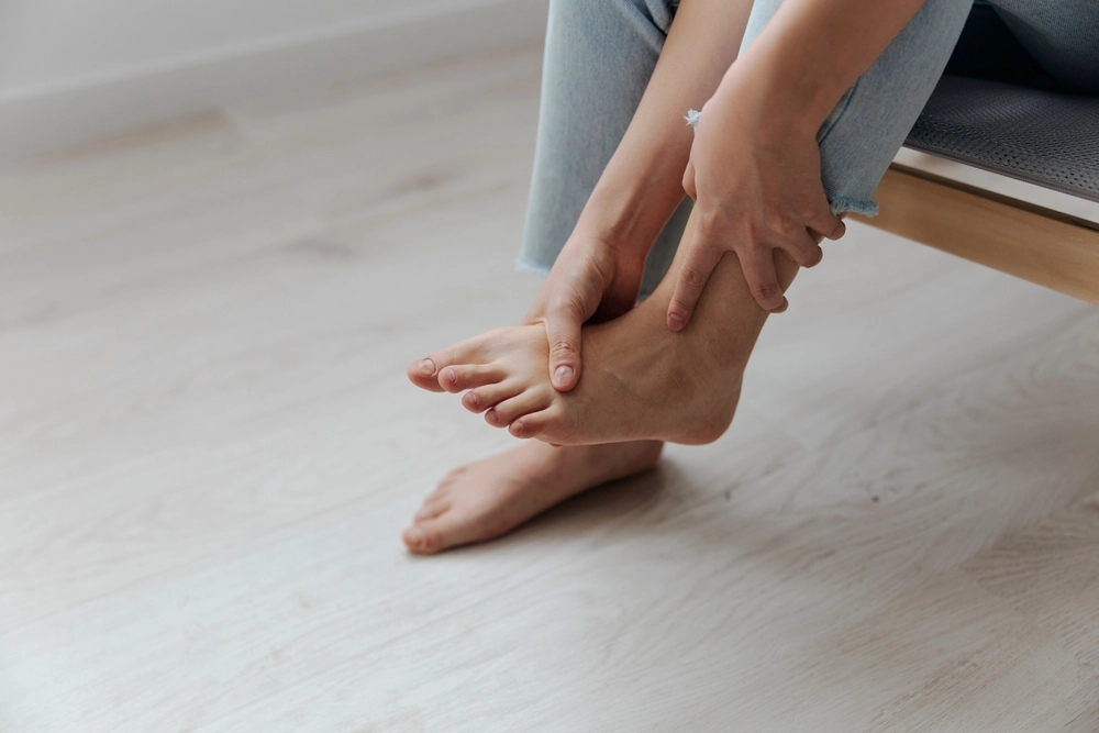 Person holding foot in pain while sitting on floor