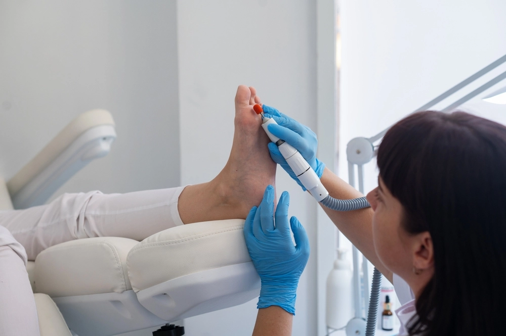 Podiatrist using handheld laser device to treat patient's foot during in-office procedure