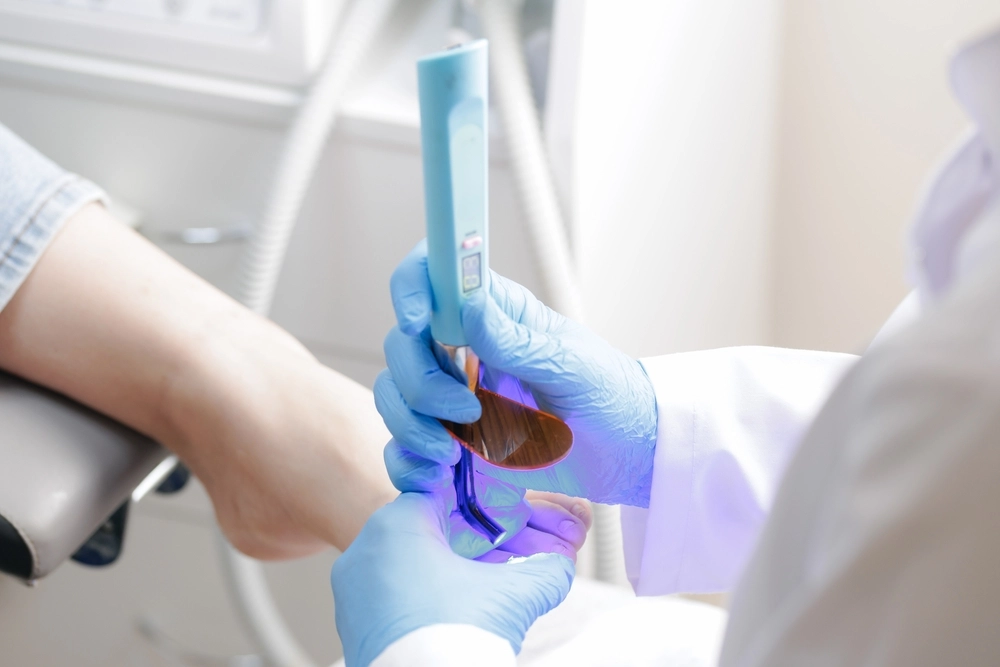 Healthcare provider holding 3D model of foot bones with purple illumination