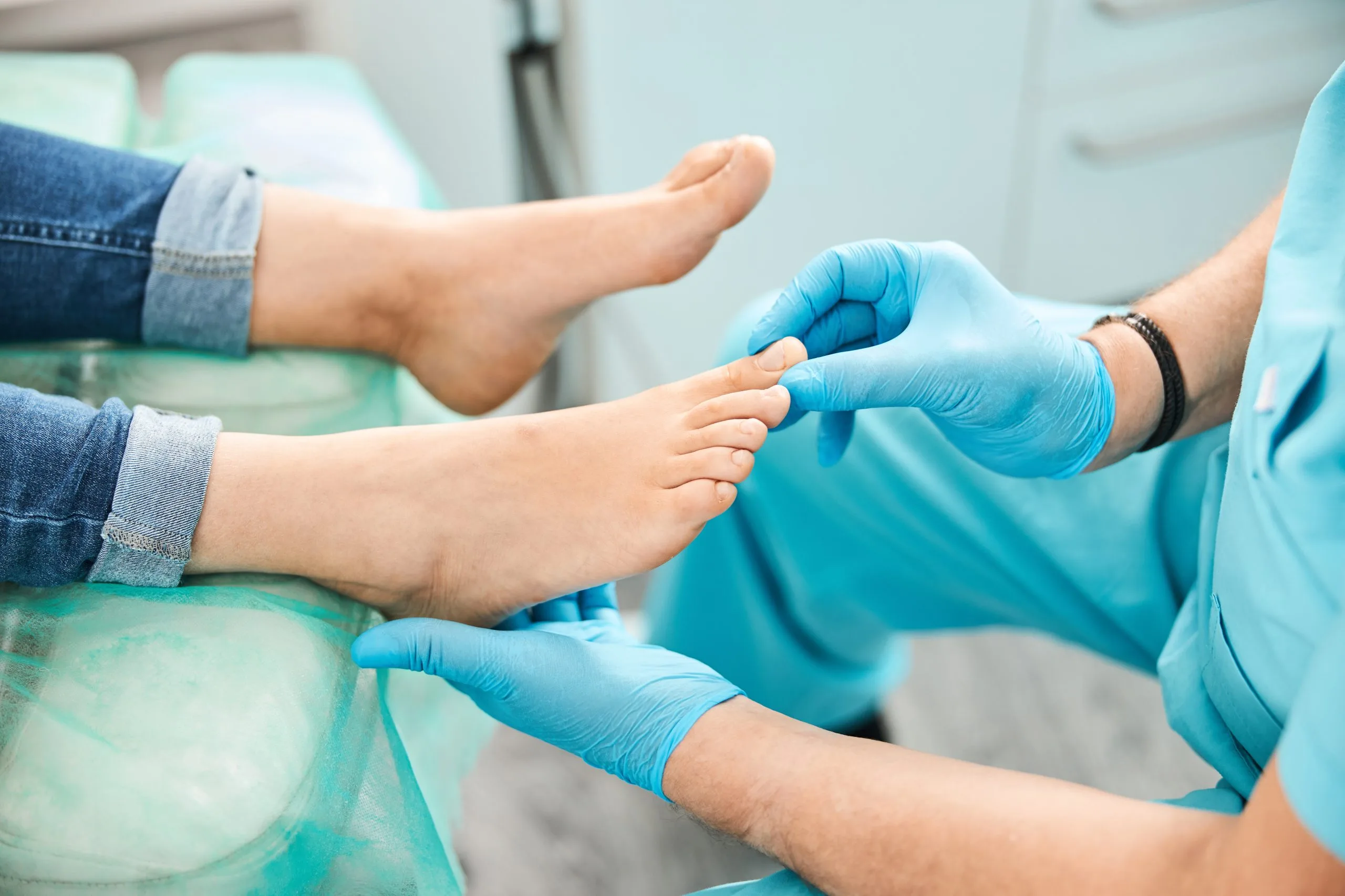 Podiatrist in blue gloves examining patient's foot during consultation