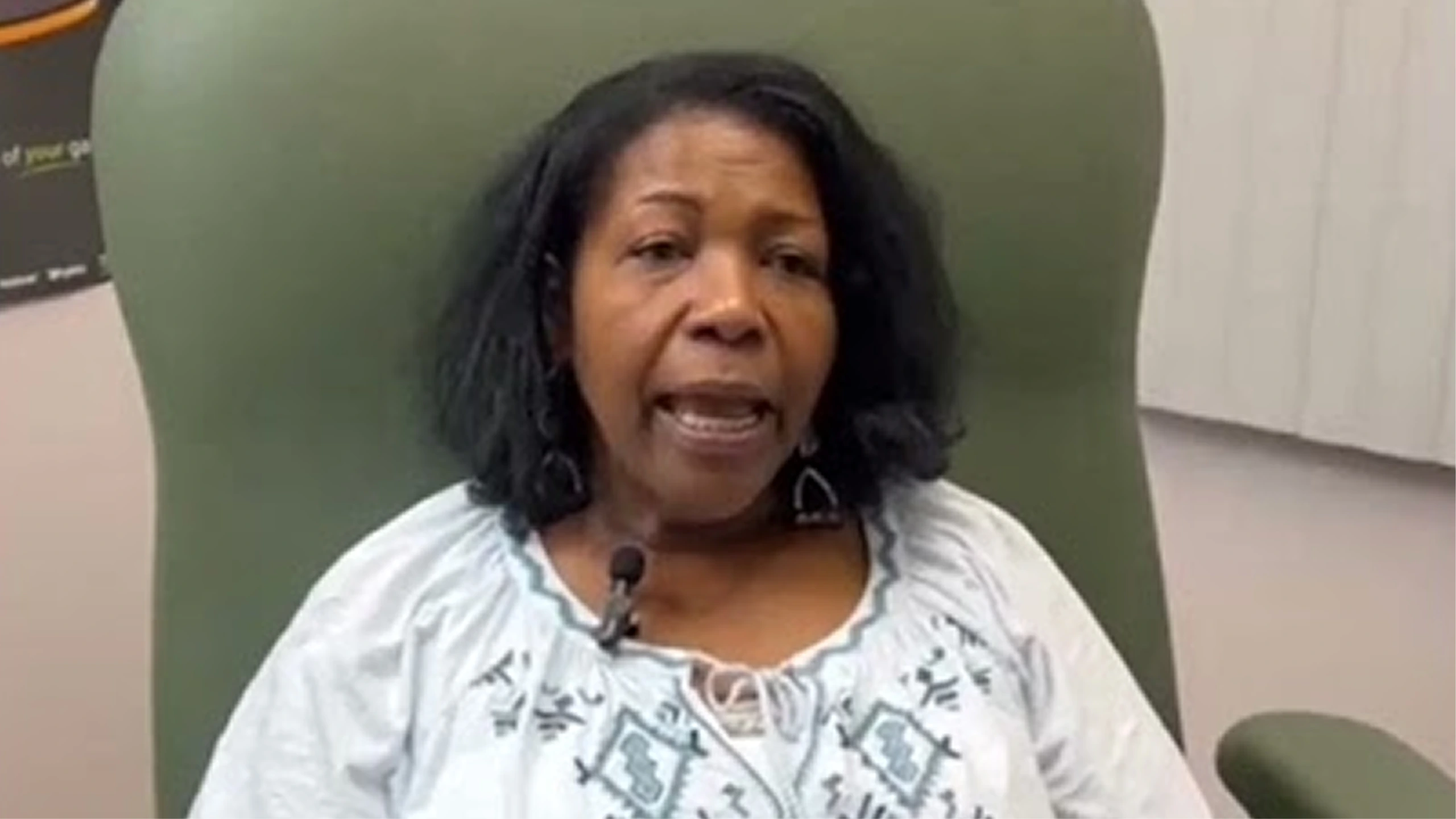 Patient in white patterned top speaking in podiatry clinic treatment room