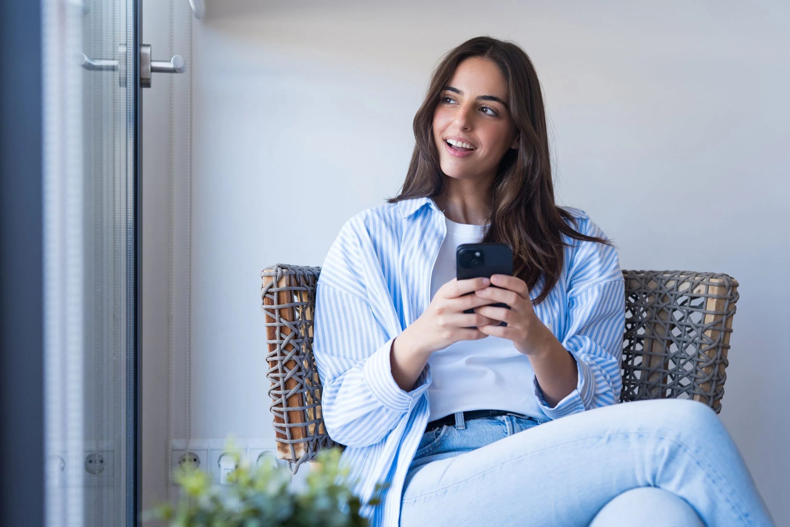 Happy young woman smiling and using her smartphone after treatment