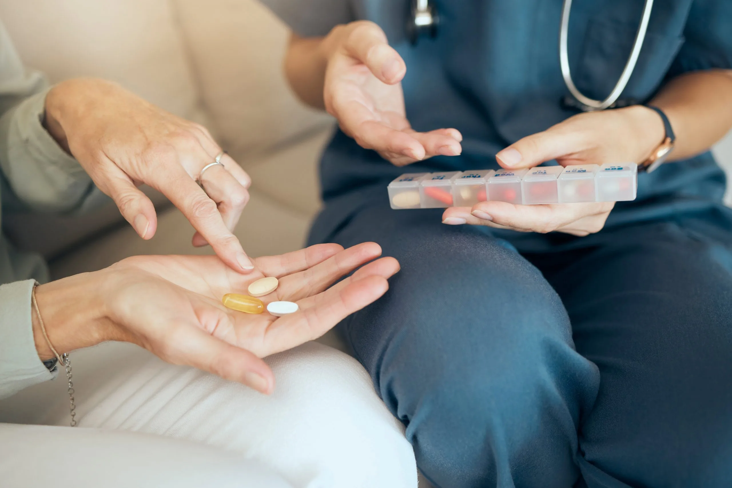 Healthcare provider with stethoscope holding medication pills in hand for patient