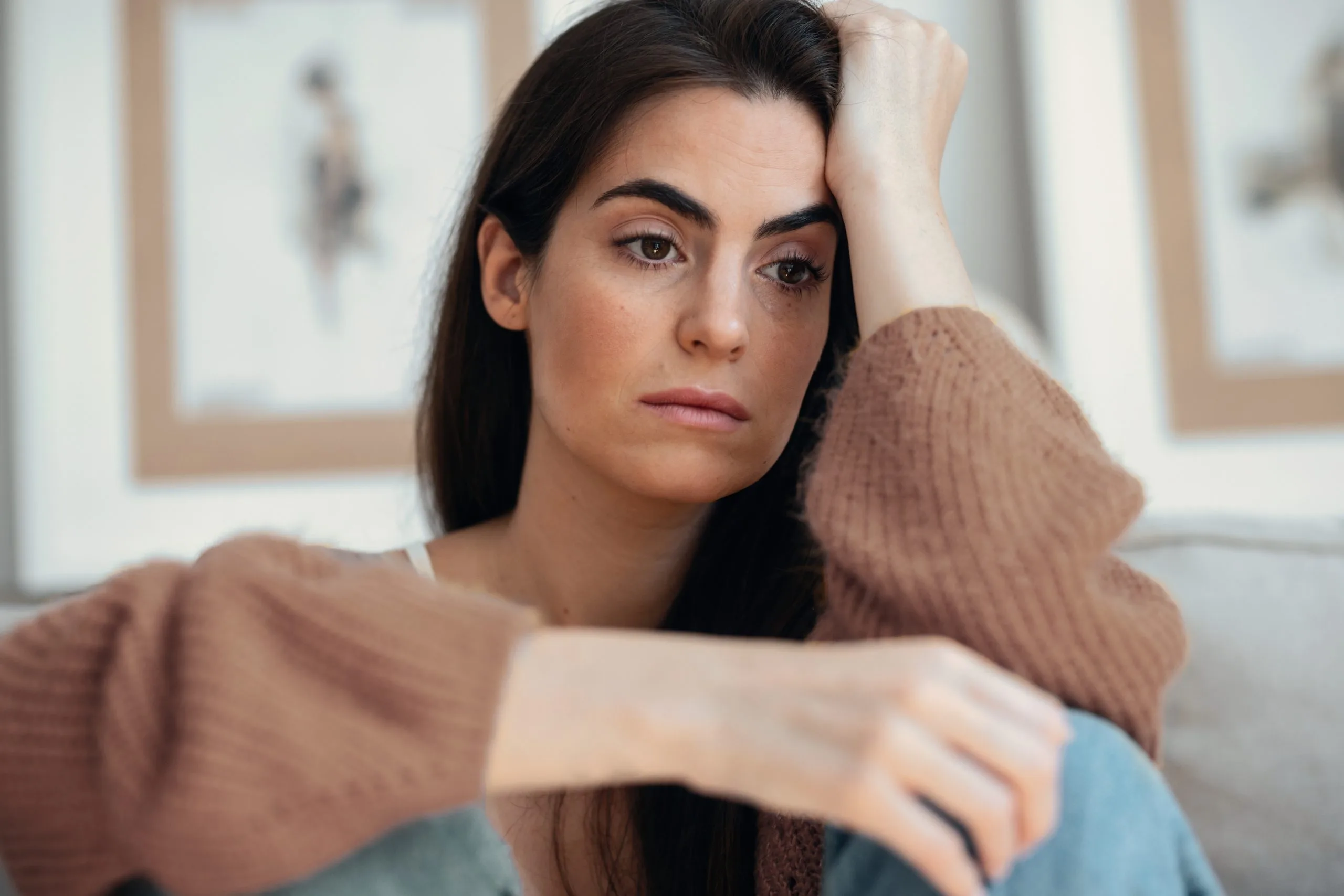 Woman with anxious expression seated on couch during mental health consultation