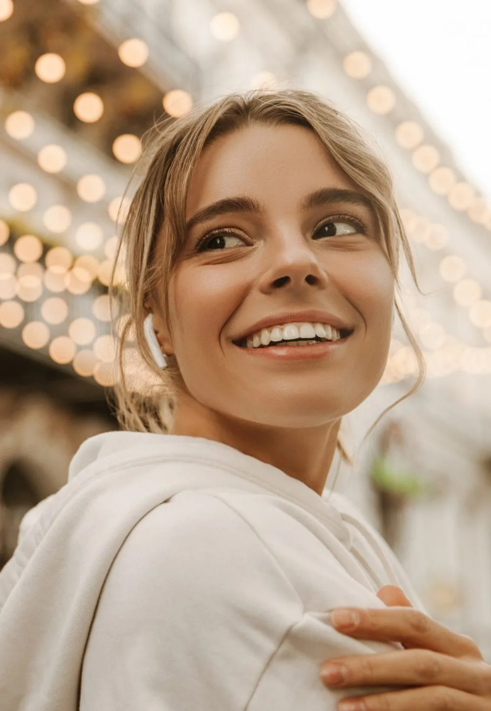 Woman smiling warmly at camera with bokeh lights in background