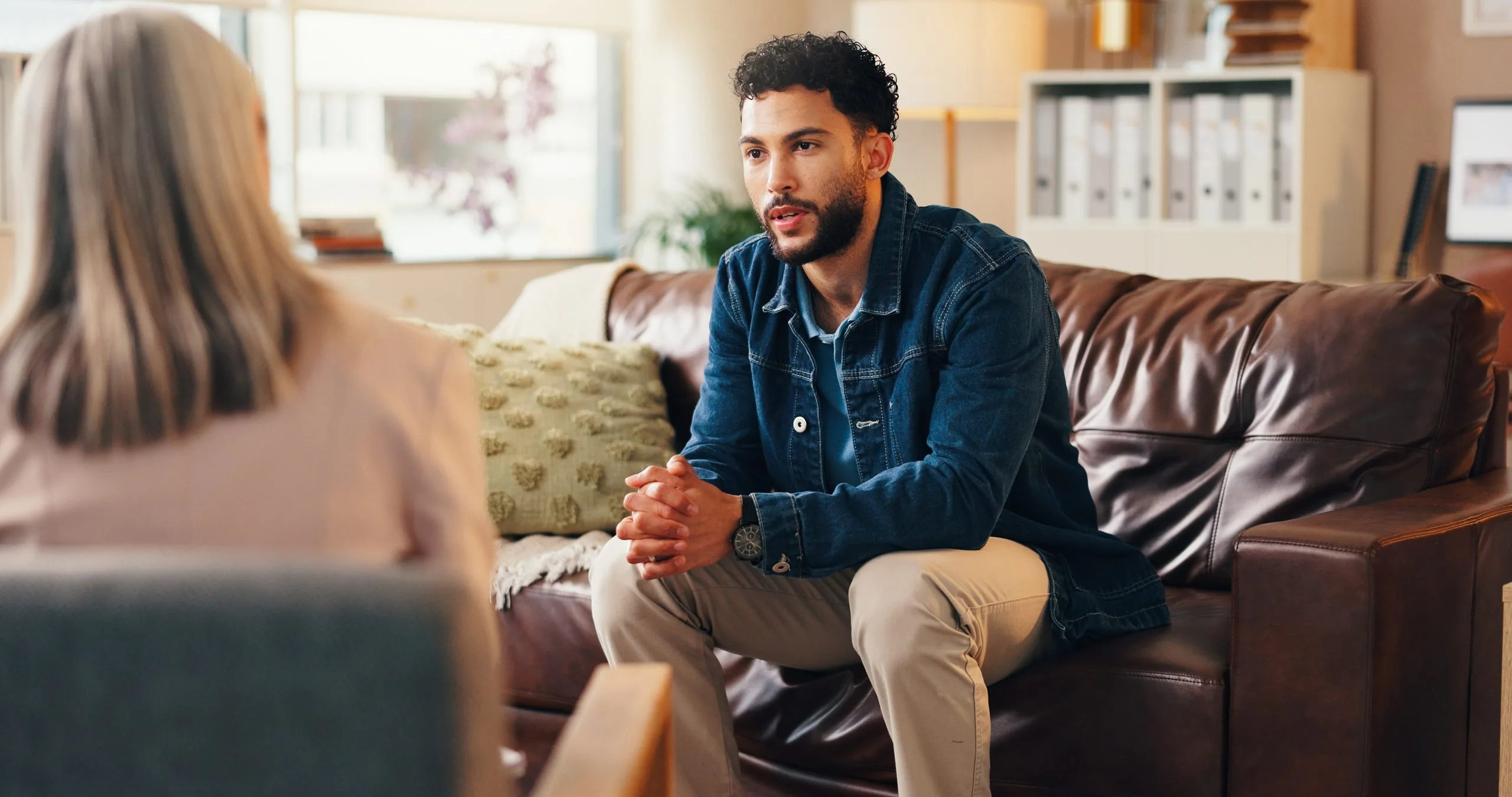 Man sitting on couch talking with female therapist during mental health consultation