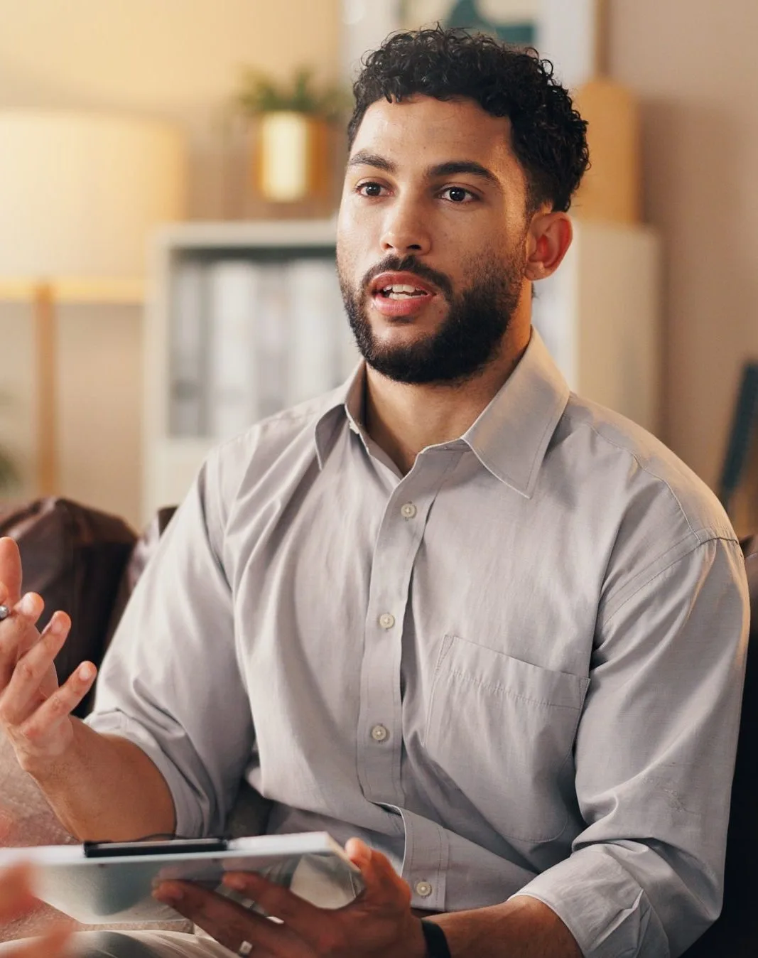 Man speaking during consultation while holding tablet with another person present