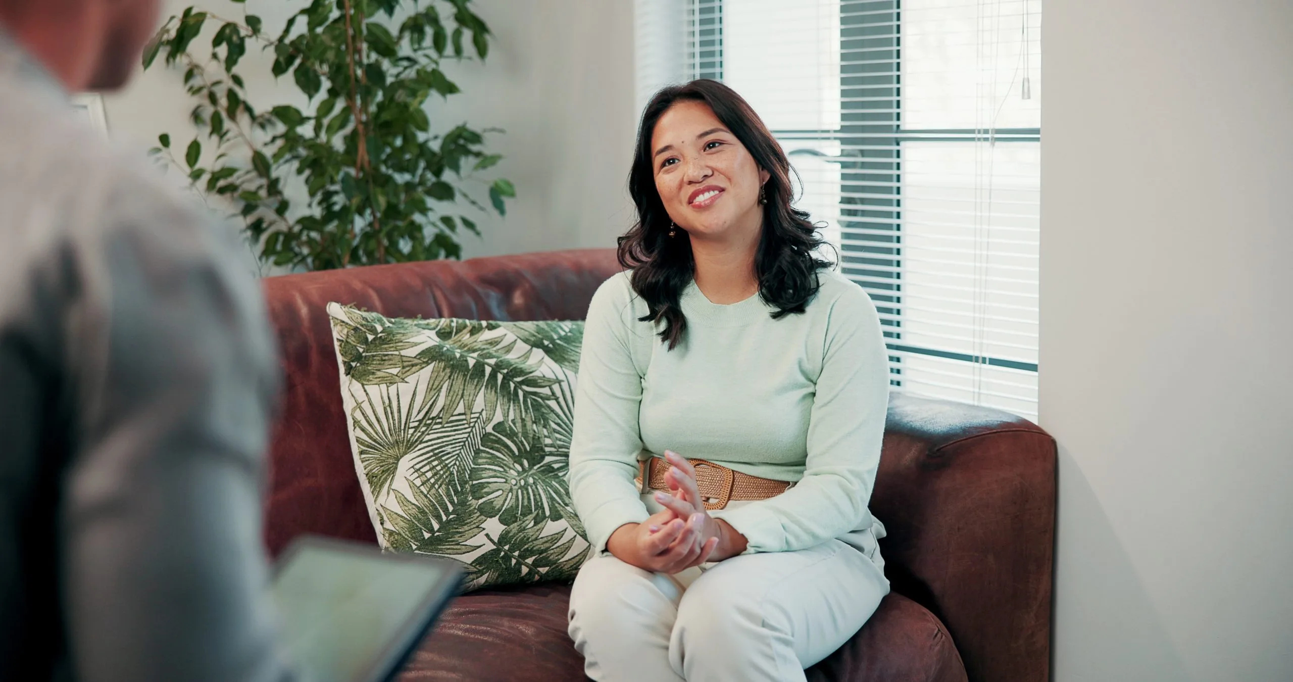 Mental health counselor speaking with patient during therapy session in bright office