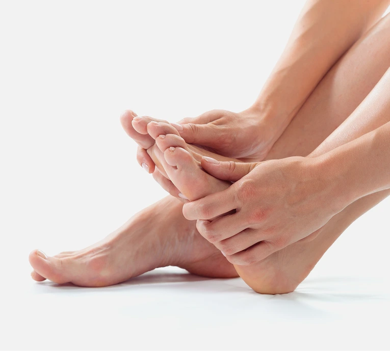 Person's hands cradling foot and ankle against white background