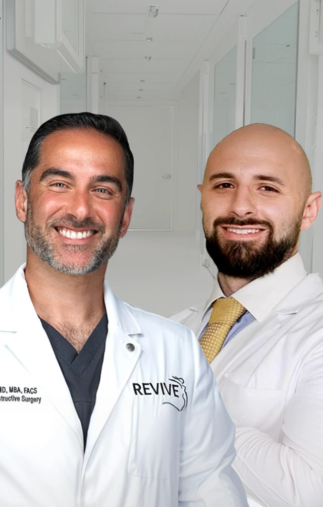 Two healthcare providers in white coats with Revive branding smiling in clinic interior