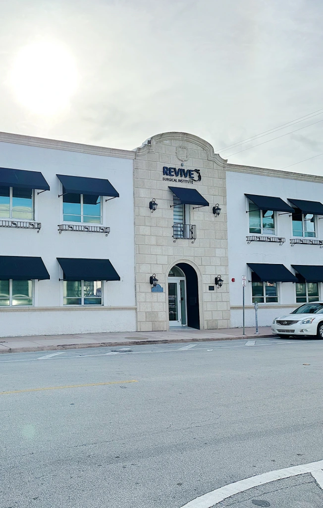 Revive's Surgical Institute building exterior with white and stone facade, blue awnings, and entrance on street