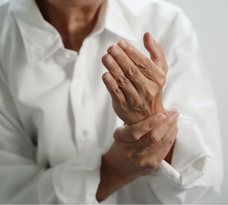 Person in white shirt holding wrist, indicating hand or joint pain