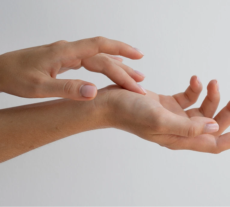 One hand palpating the back of another hand to examine for lumps or abnormalities