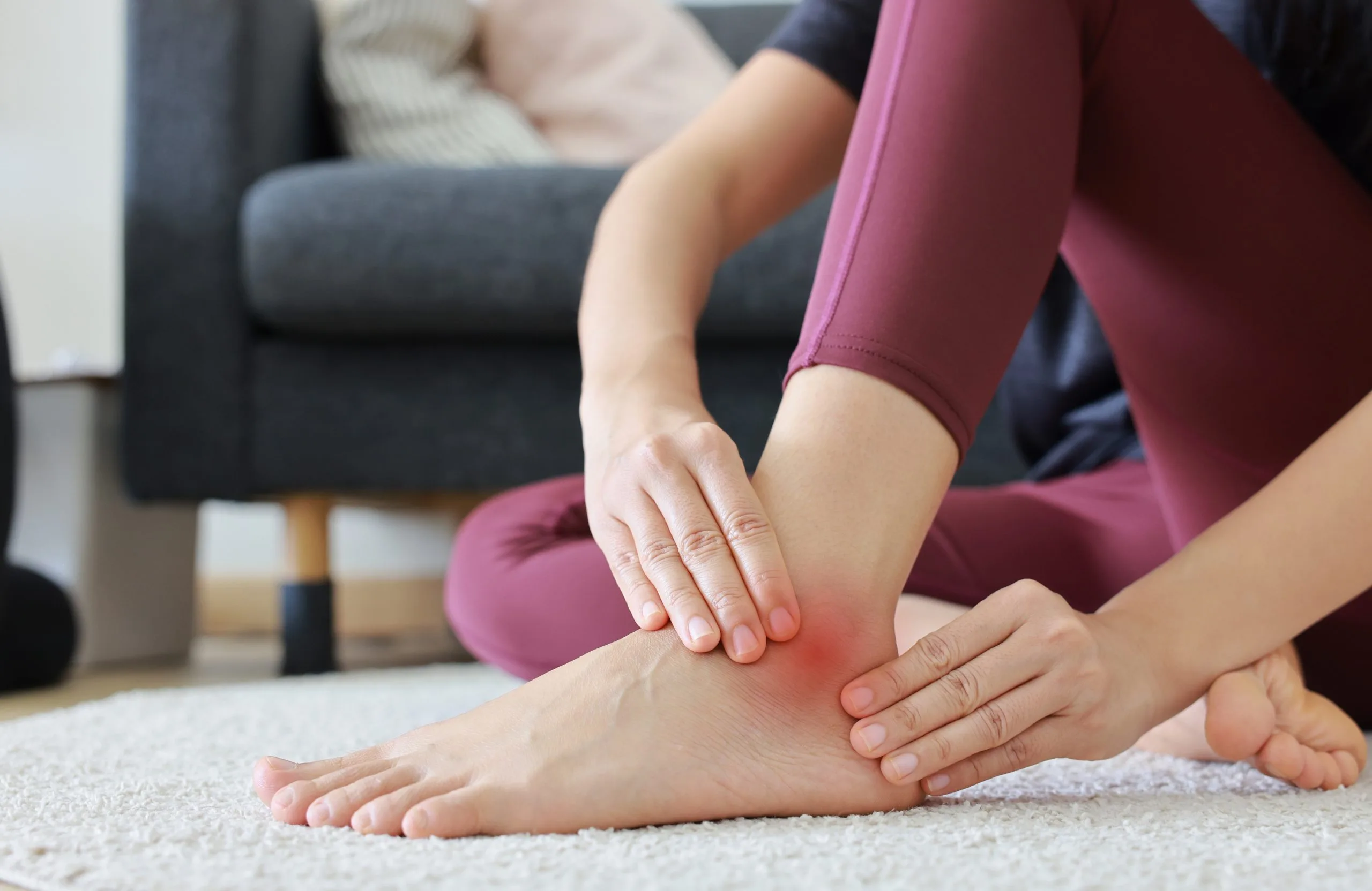 Person in workout attire holding their lower leg with visible redness indicating discomfort